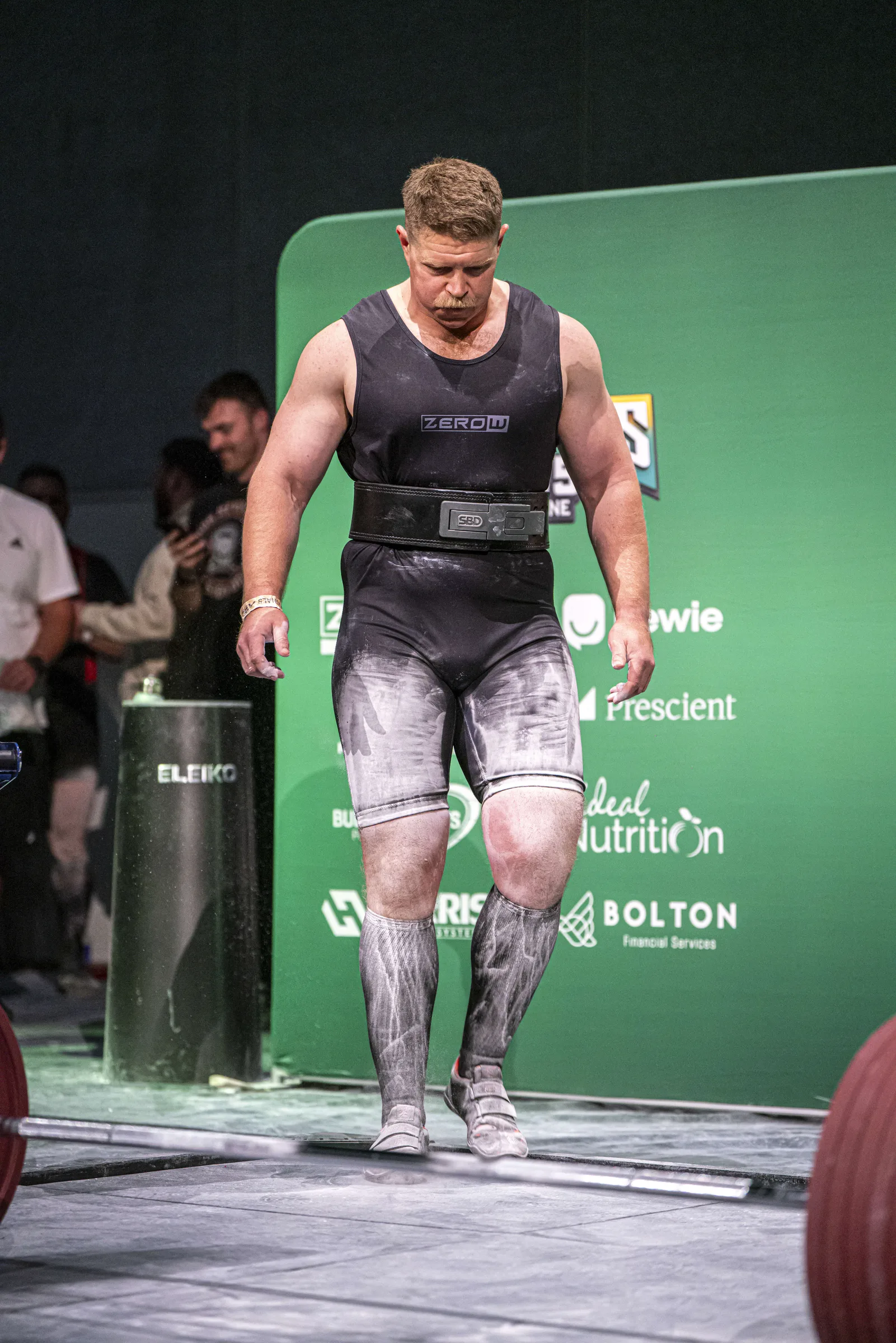 Abe Dearmer walking out onto the competition platform in a singlet, chalk on his hands.